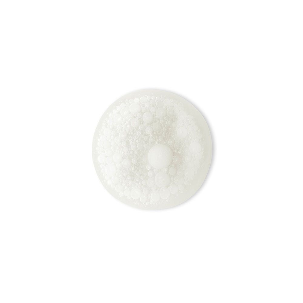 Gros plan d'un liquide blanc mousseux sur fond blanc. Un point clair plus petit au centre.