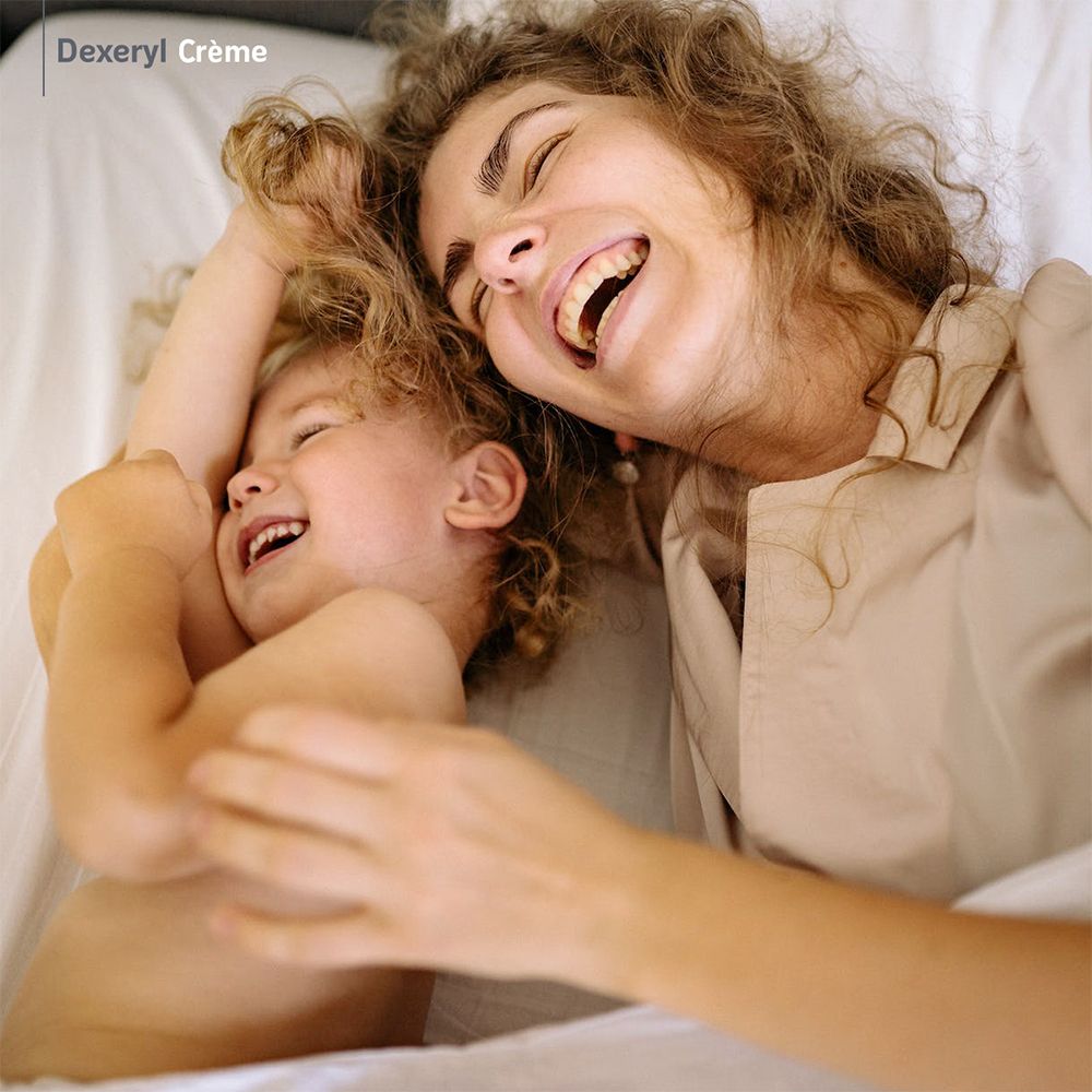 Mère et enfant rient. Logo Dexeryl Crème en haut à gauche.