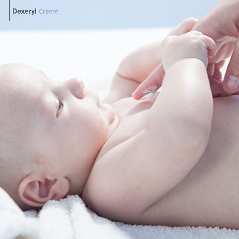 Bébé se fait appliquer de la crème. Logo Dexeryl Crème en haut à gauche.