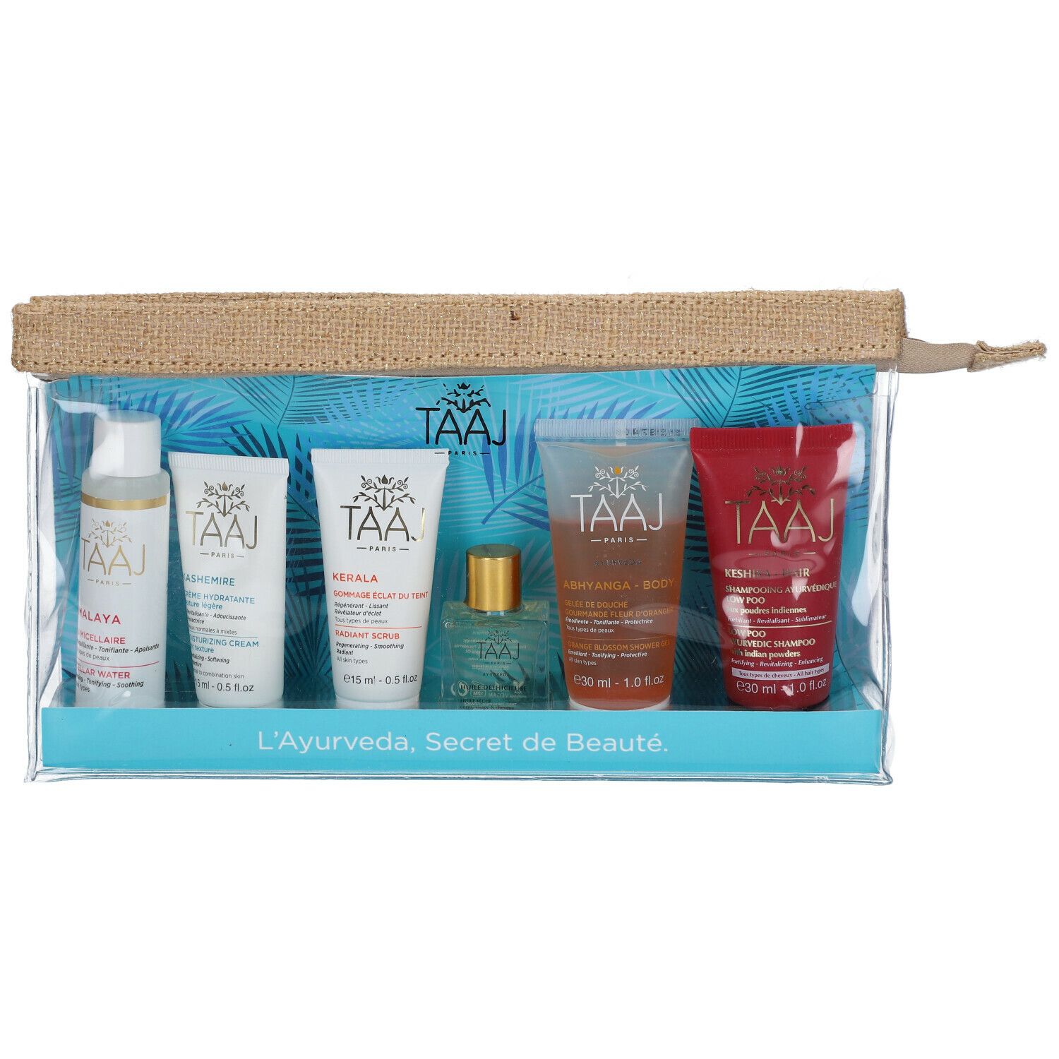 Klare Kosmetiktasche mit sechs Produkten. Aufschrift: TAAJ. Produkte in Flaschen und Tuben. Aufschrift: L'Ayurveda, Secret de Beauté.