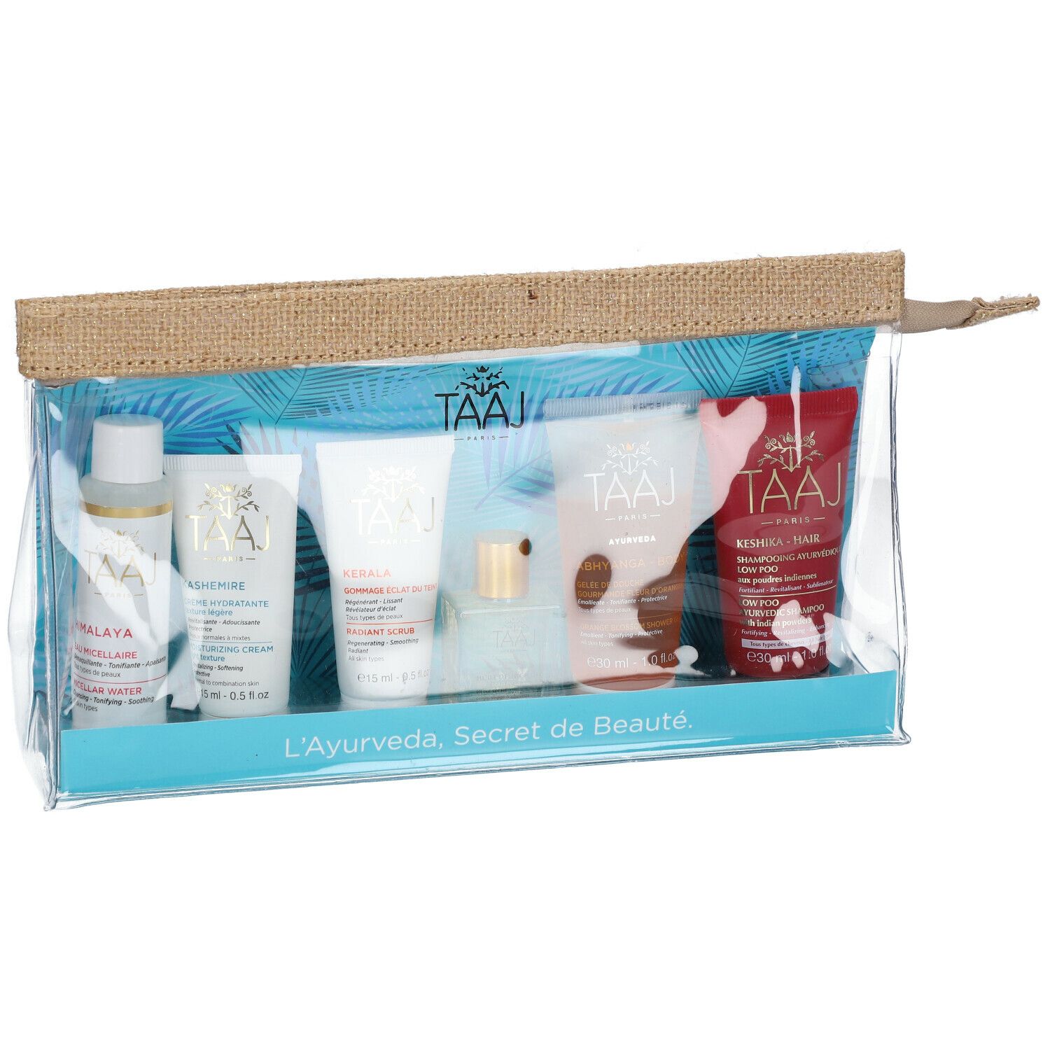 Klare Kosmetiktasche mit sechs Produkten. Aufschrift: TAAJ. Produkte in Flaschen und Tuben. Aufschrift: L'Ayurveda, Secret de Beauté.