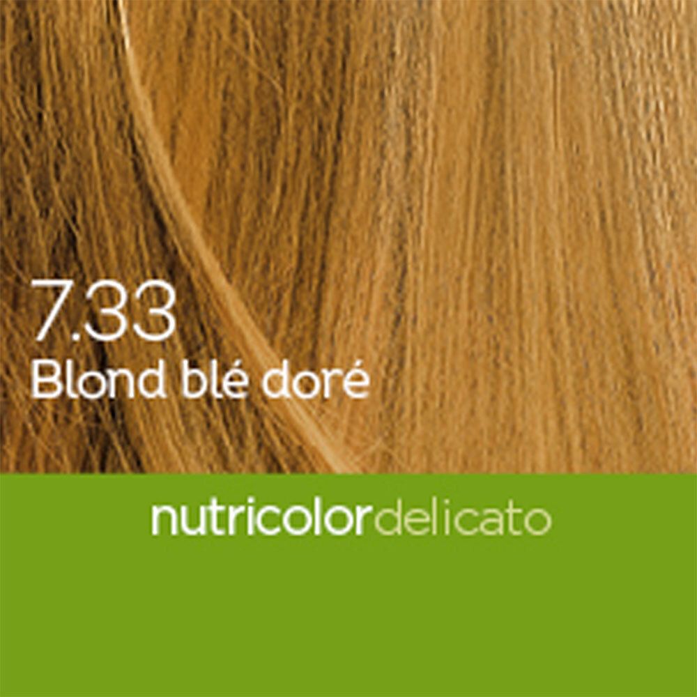 Détail d'une publicité pour une teinture capillaire. Montre des mèches blondes avec l'inscription 7.33 Blond blé doré et Nutricolor Delicato.