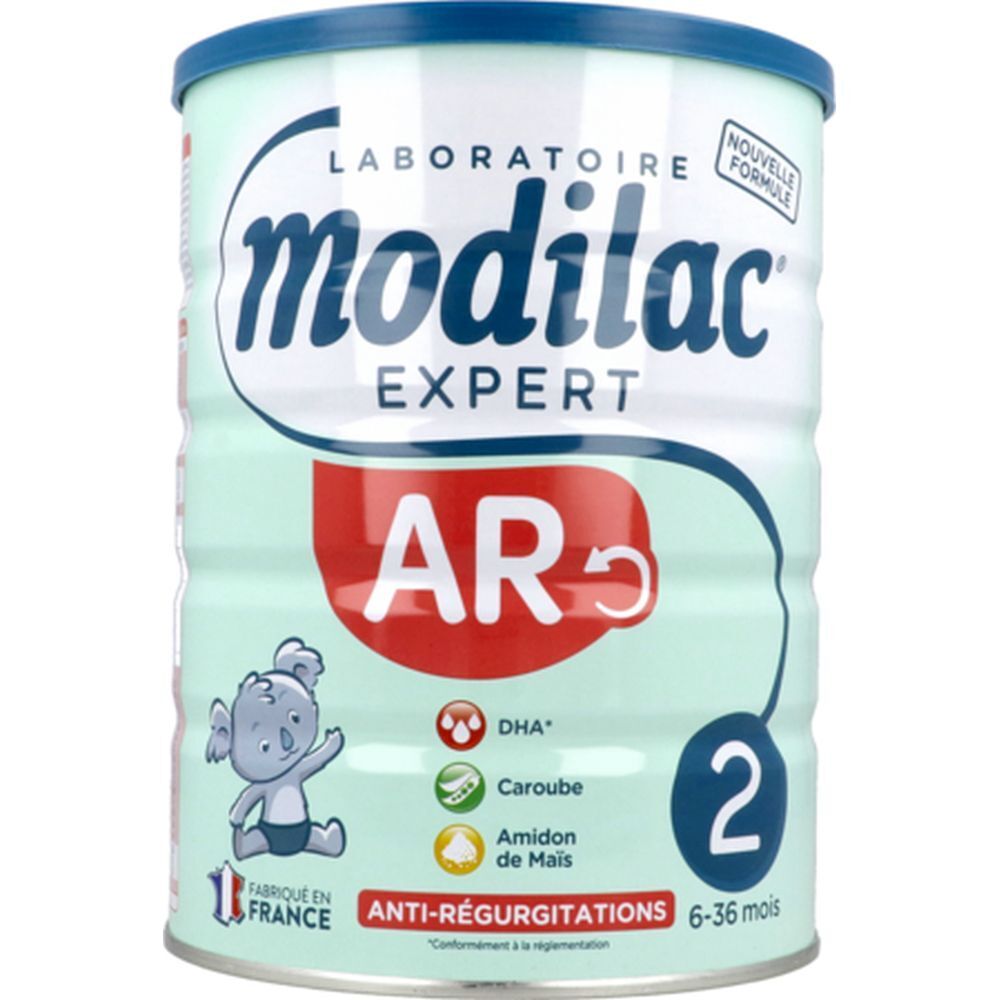 Boîte verte claire avec couvercle bleu. Inscription 'modilac EXPERT AR'. Contient 'DHA', 'Caroube', 'Amidon de Mais'. Recommandé pour les 6-36 mois.