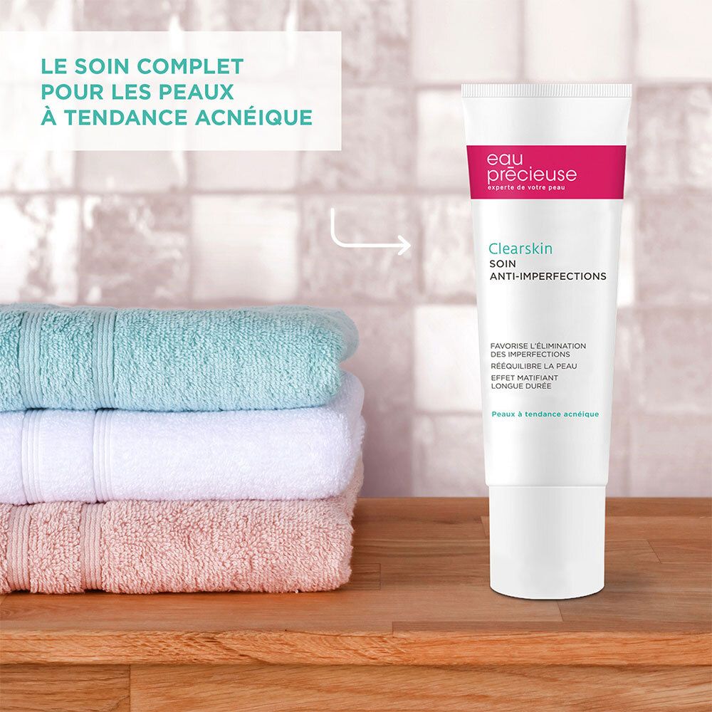 Tube Eau Précieuse Clearskin Anti-Imperfections à côté de serviettes. Surface en bois.