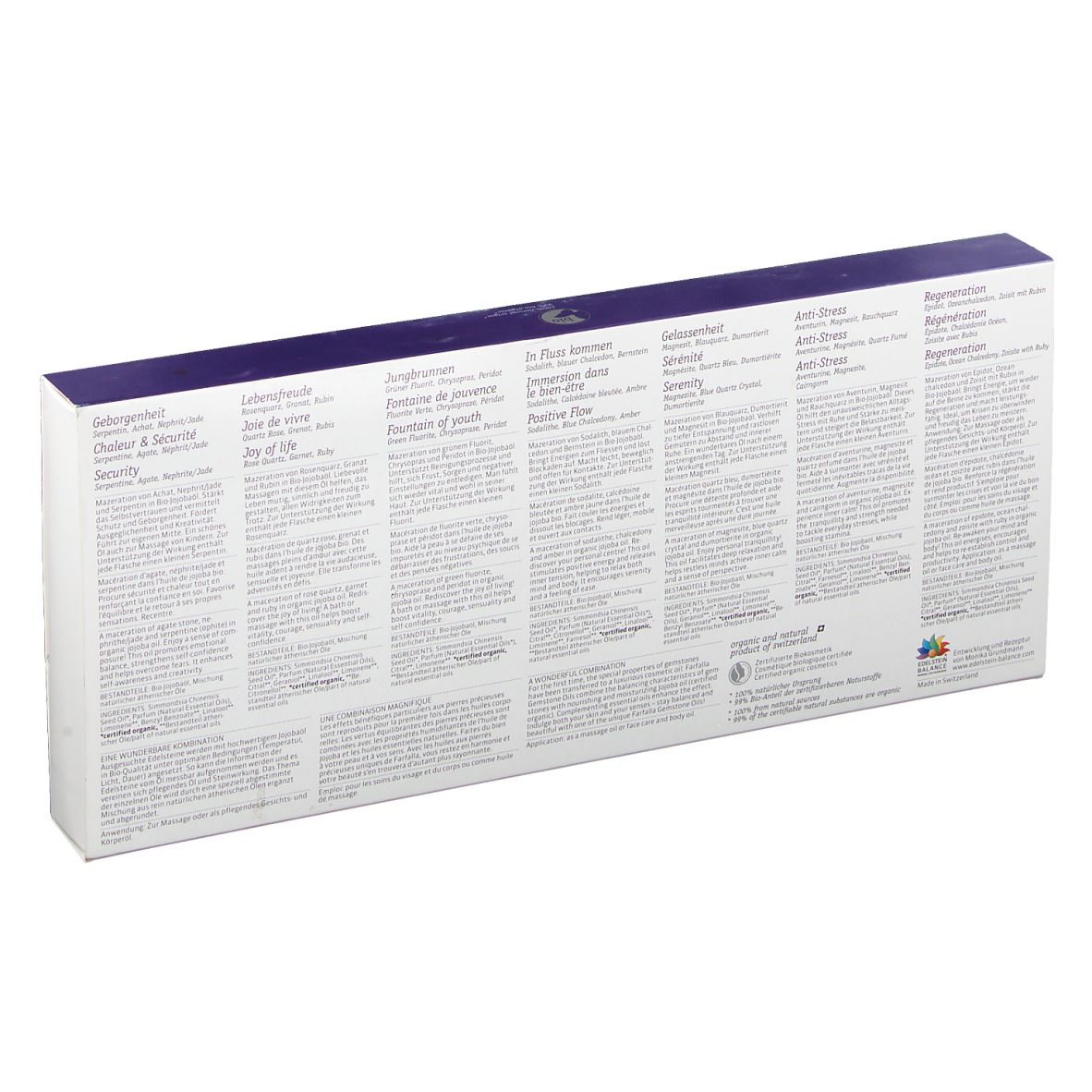 Dos du coffret avec textes multilingues. Informations sur les huiles de pierres précieuses. Fond blanc, couvercle violet.
