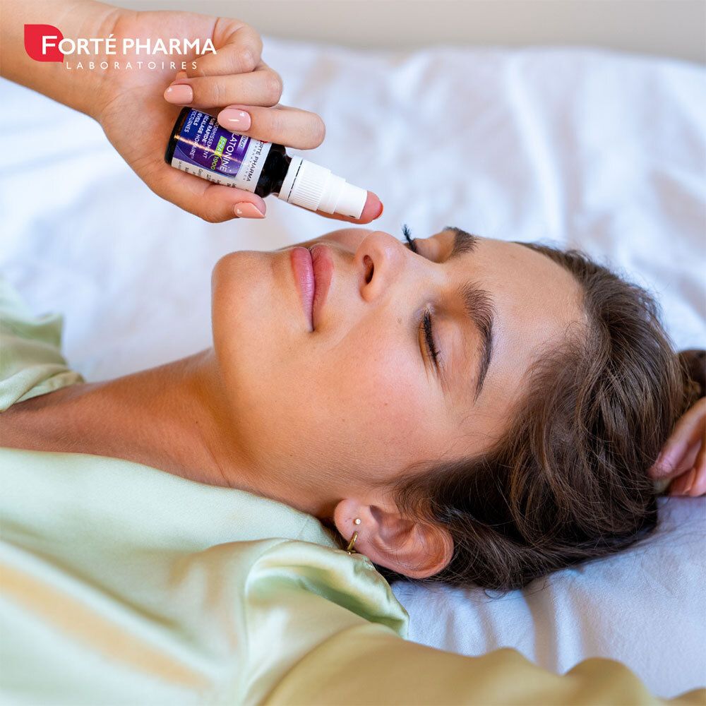 Main vaporisant le produit sur le visage d'une personne. Flacon spray: Forté Pharma, Mélatonine Spray 1900.