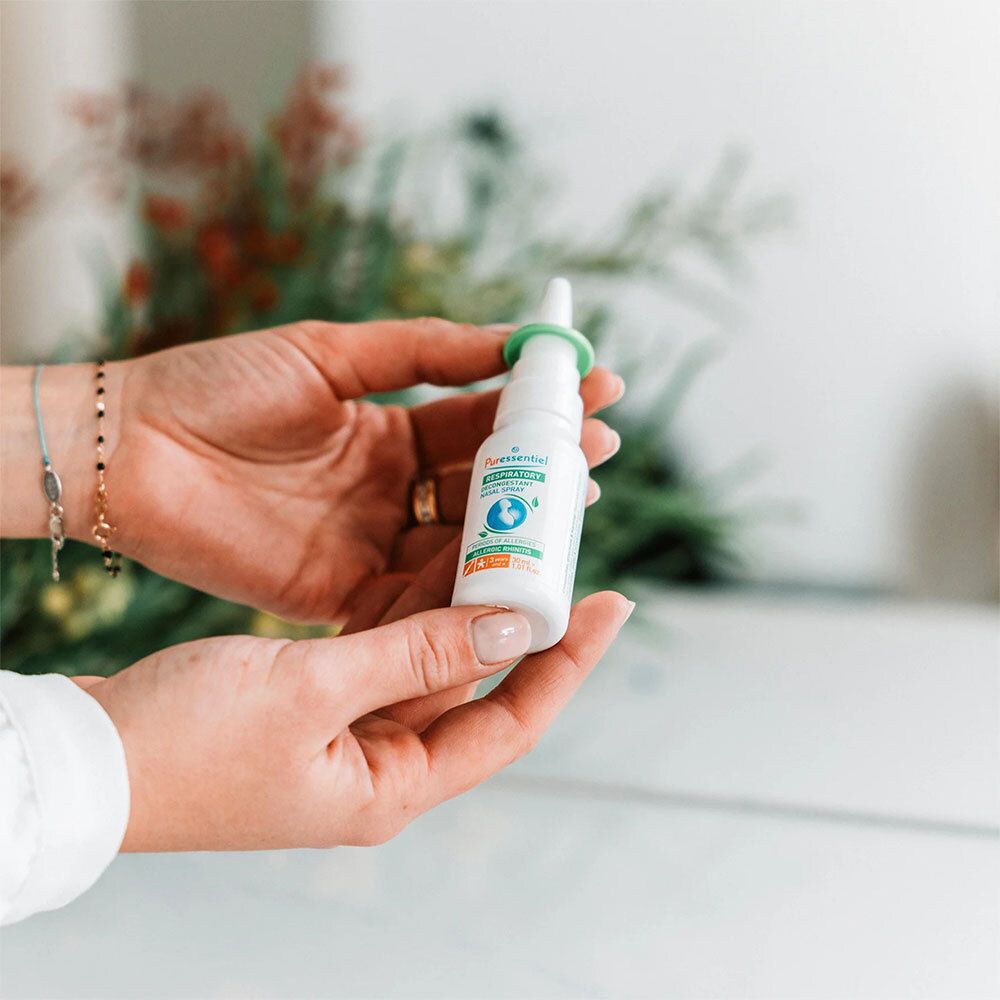 Personne tenant un spray nasal. Inscription: Puressentiel RESPIRATOIRE. Allergie. Flacon blanc.