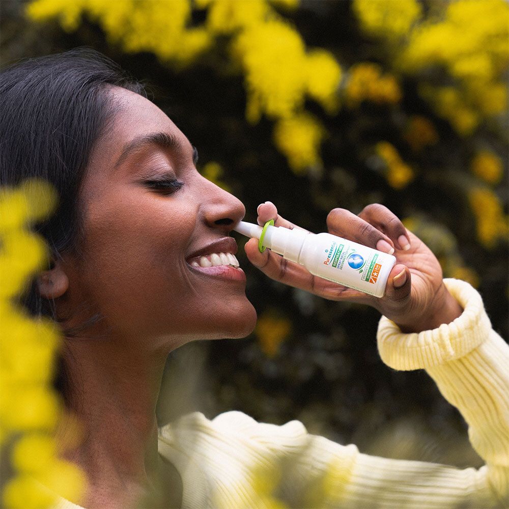 Personne utilisant un spray nasal. Inscription: Puressentiel RESPIRATOIRE. Allergie. Fleurs jaunes.