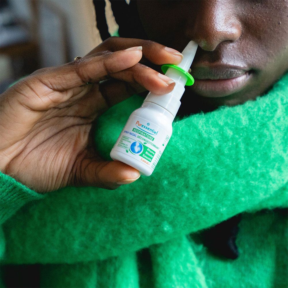 Spray nasal avec bouchon vert, entouré de plantes. Texte: PURESSENTIEL RESPIRATOIRE. Pour les allergiques.
