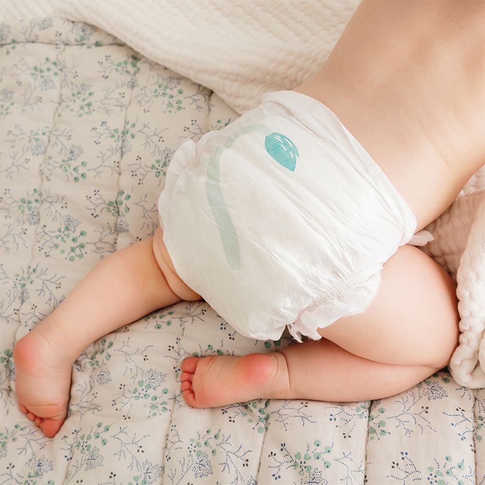 Bébé portant une couche. Couche avec motif de feuille bleue. Bébé couché sur un motif floral.
