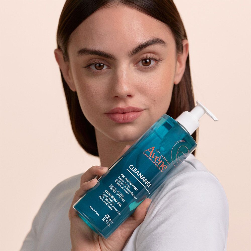 Femme tenant flacon turquoise avec pompe blanche. Inscription: Avene Cleanance, Gel Nettoyant.