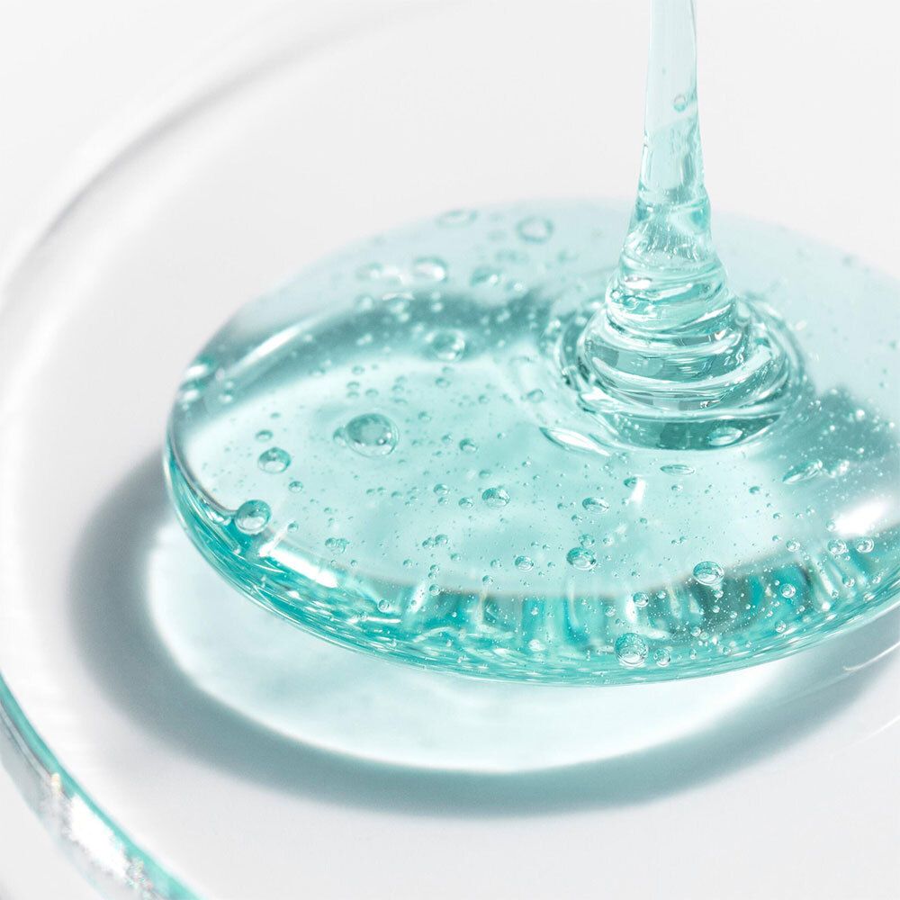 Gel turquoise sur une surface transparente. Aucune indication de produit visible.