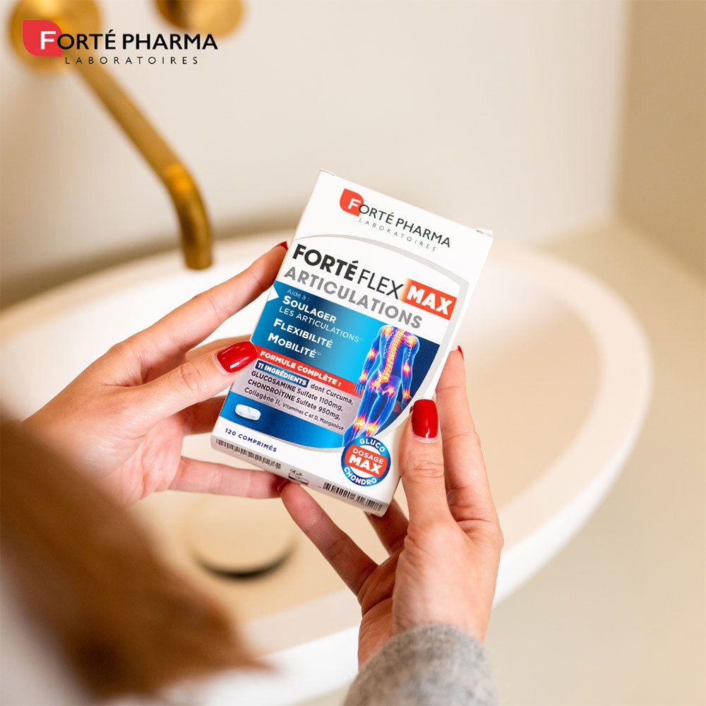 Une personne tient une boîte de Forté Pharma Forté Flex Max Articulations. La boîte est blanche avec des accents bleus et rouges.