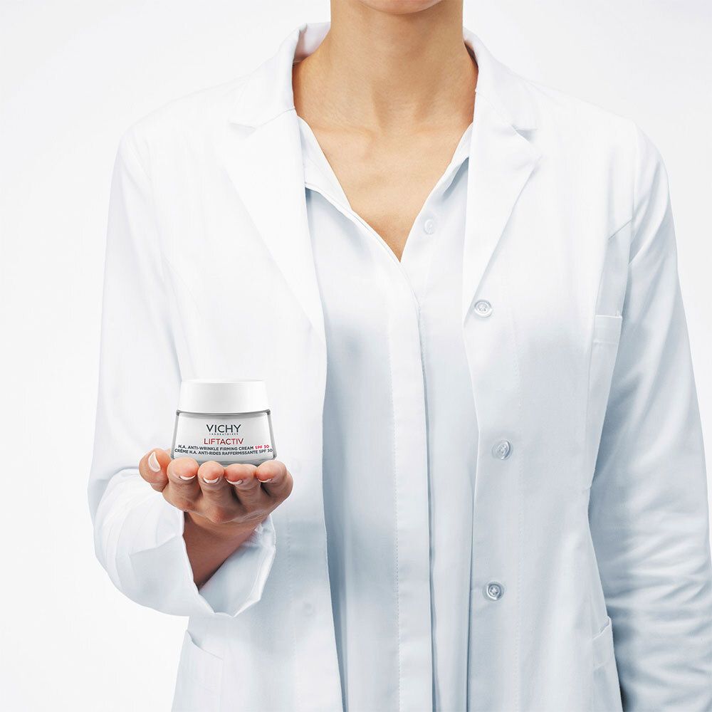 Personne tenant un pot de crème. La personne porte une blouse blanche. Produit: VICHY LiftActiv Supreme.