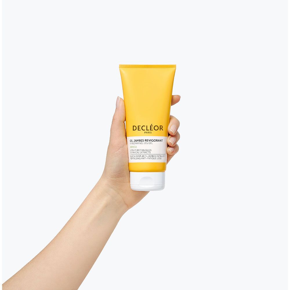 Tube de gel dans la main. Tube jaune avec bouchon blanc. DECLÉOR PARIS. Gel Jambes Revigorant.