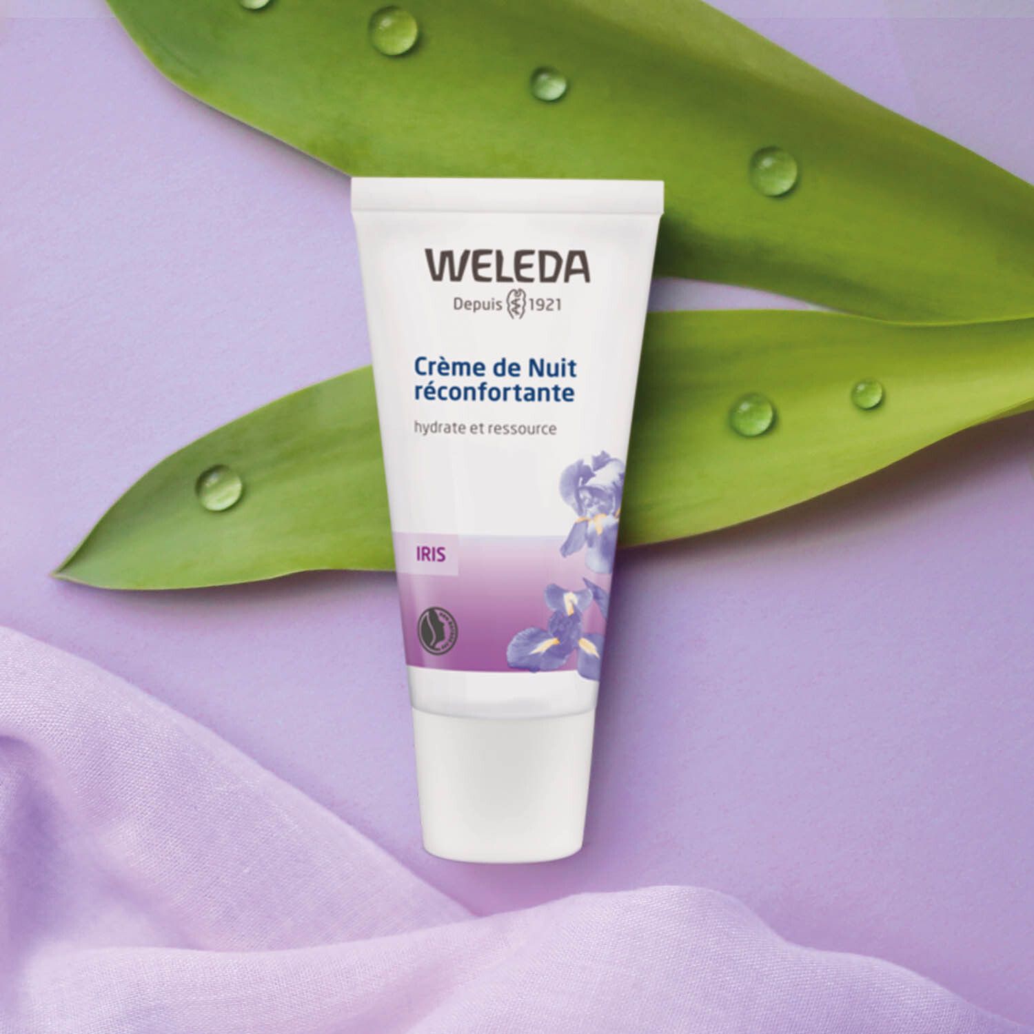 Weleda-Tube auf Blatt. Produktname und Iris-Abbildung. Lila Hintergrund.