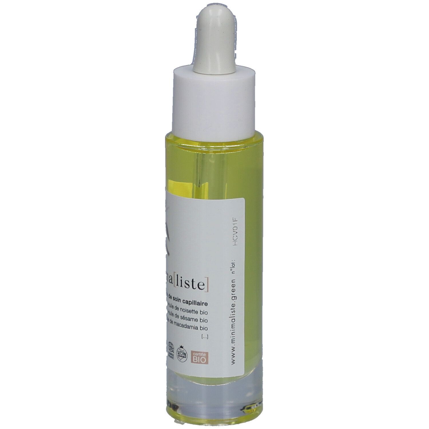 Flacon d'huile capillaire avec pipette. Étiquette avec nom du produit et certifications. Liquide jaune visible.