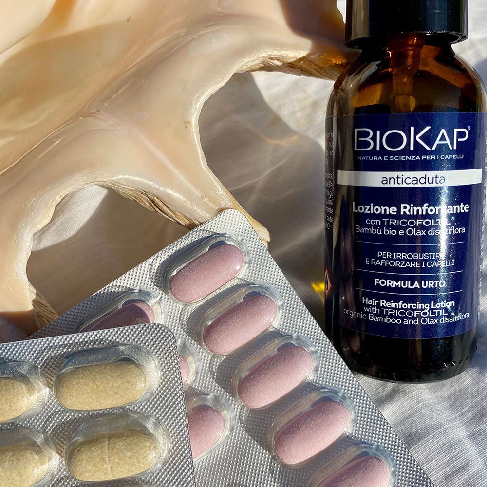 BIOKAP Lotion Anti Chute Renforçante. Flacon, plaquettes de comprimés et coquillage. Inscription : anticaduta, Lotion Rinforzante.