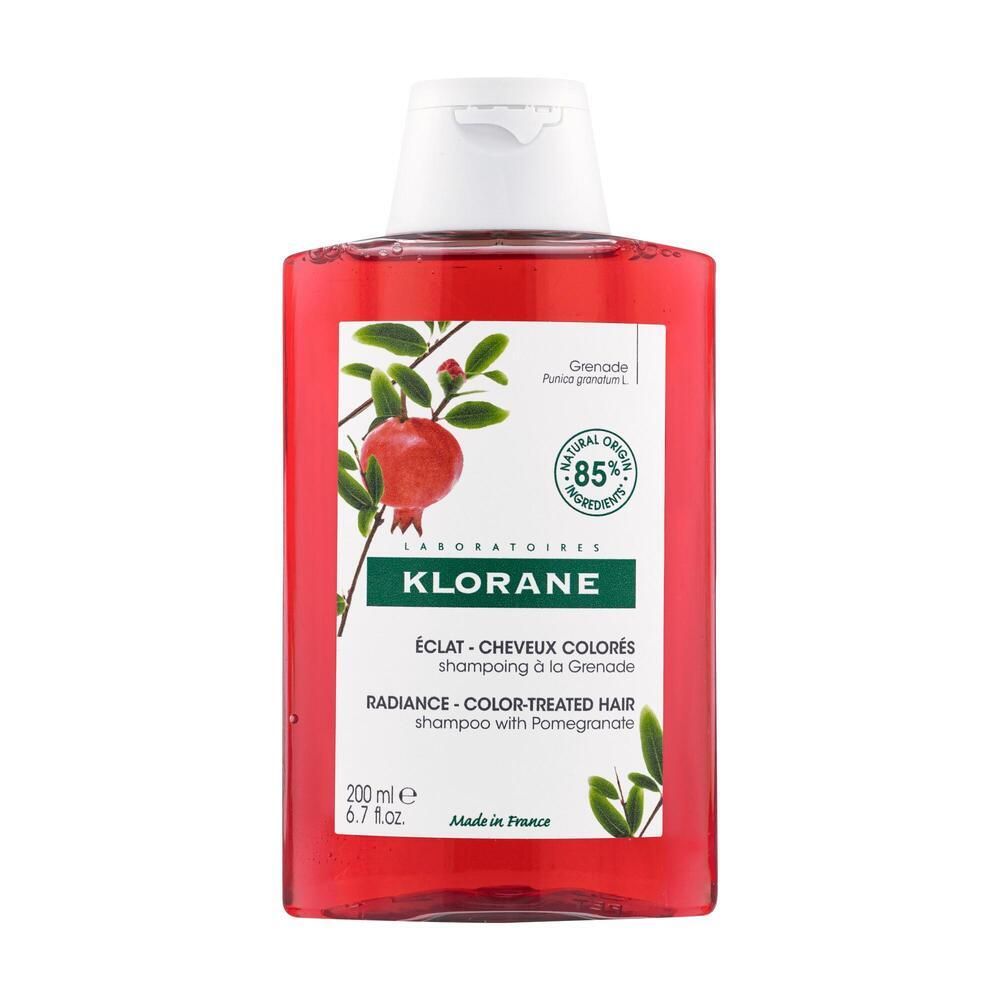 Flacon de shampooing rouge avec bouchon blanc. Étiquette avec illustration de grenade et texte: KLORANE, ÉCLAT - CHEVEUX COLORÉS.