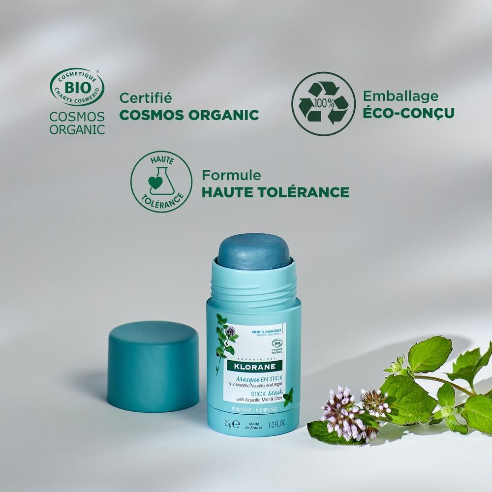 Hellblaue Stick-Maske mit geöffnetem Deckel. Logos: Cosmos Organic, Eco-Conçu, Haute Tolérance. Produkt auf grünem Hintergrund.