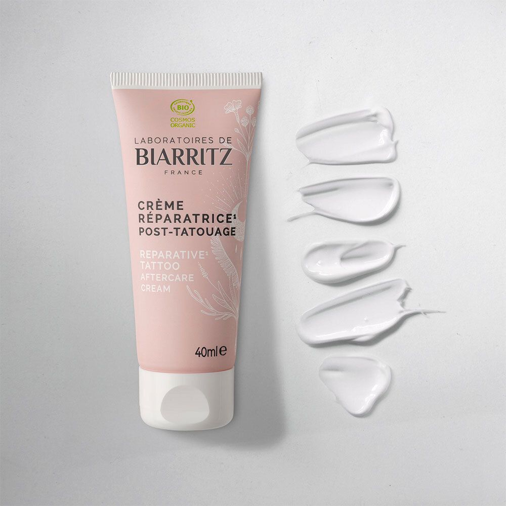 Tube rose avec bouchon blanc et gouttes de crème blanche. Inscription: CicaRepa, Crème Réparatrice Post-Tatouage, 40ml. Marque: Laboratoires de Biarritz.