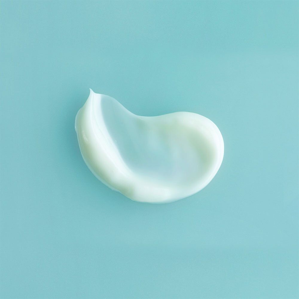 Éclaboussure de crème sur fond bleu. Texture blanche et brillante.