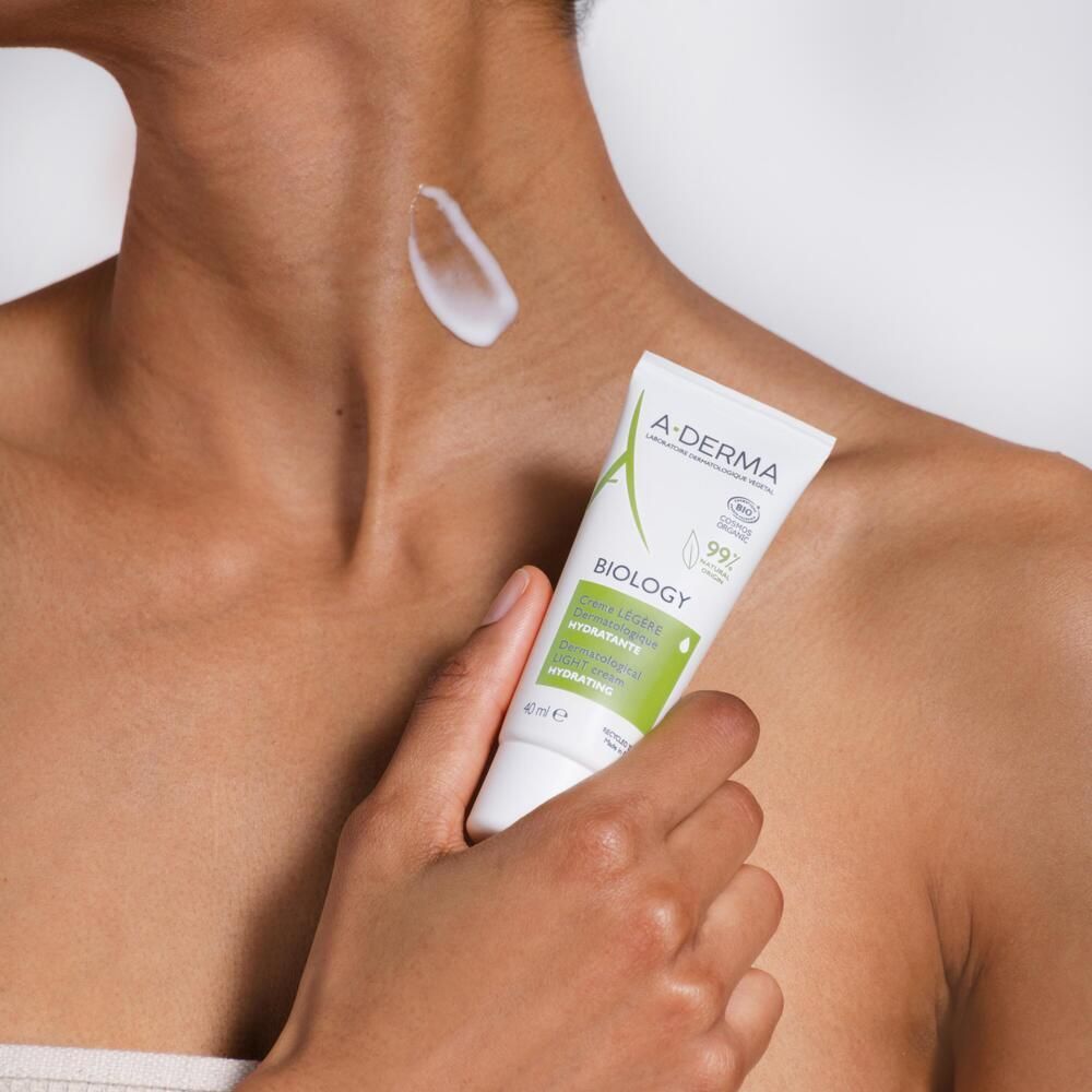 Personne appliquant la crème A-DERMA BIOLOGY sur le cou. Tube blanc, étiquette verte.