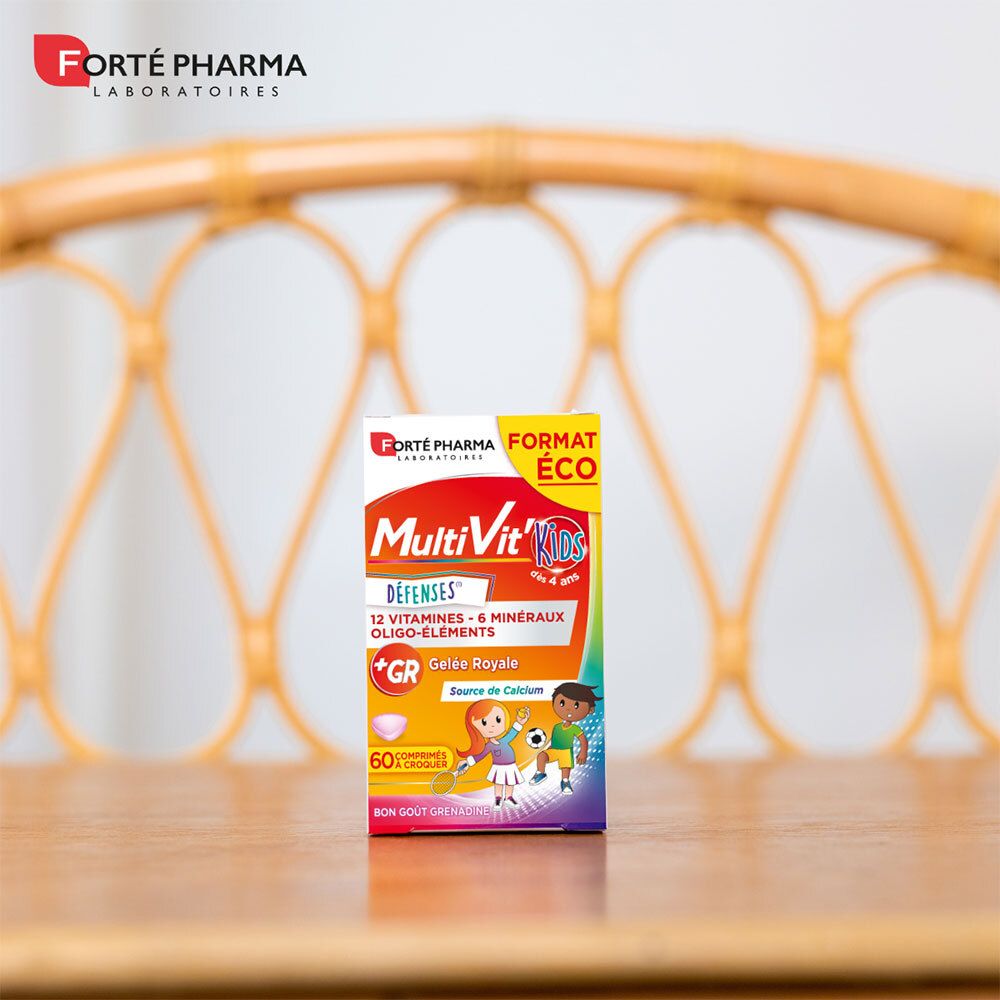 Boîte de Forté Pharma MultiVit'Kids Défenses sur une table. Informations produit visibles. Arrière-plan flou.