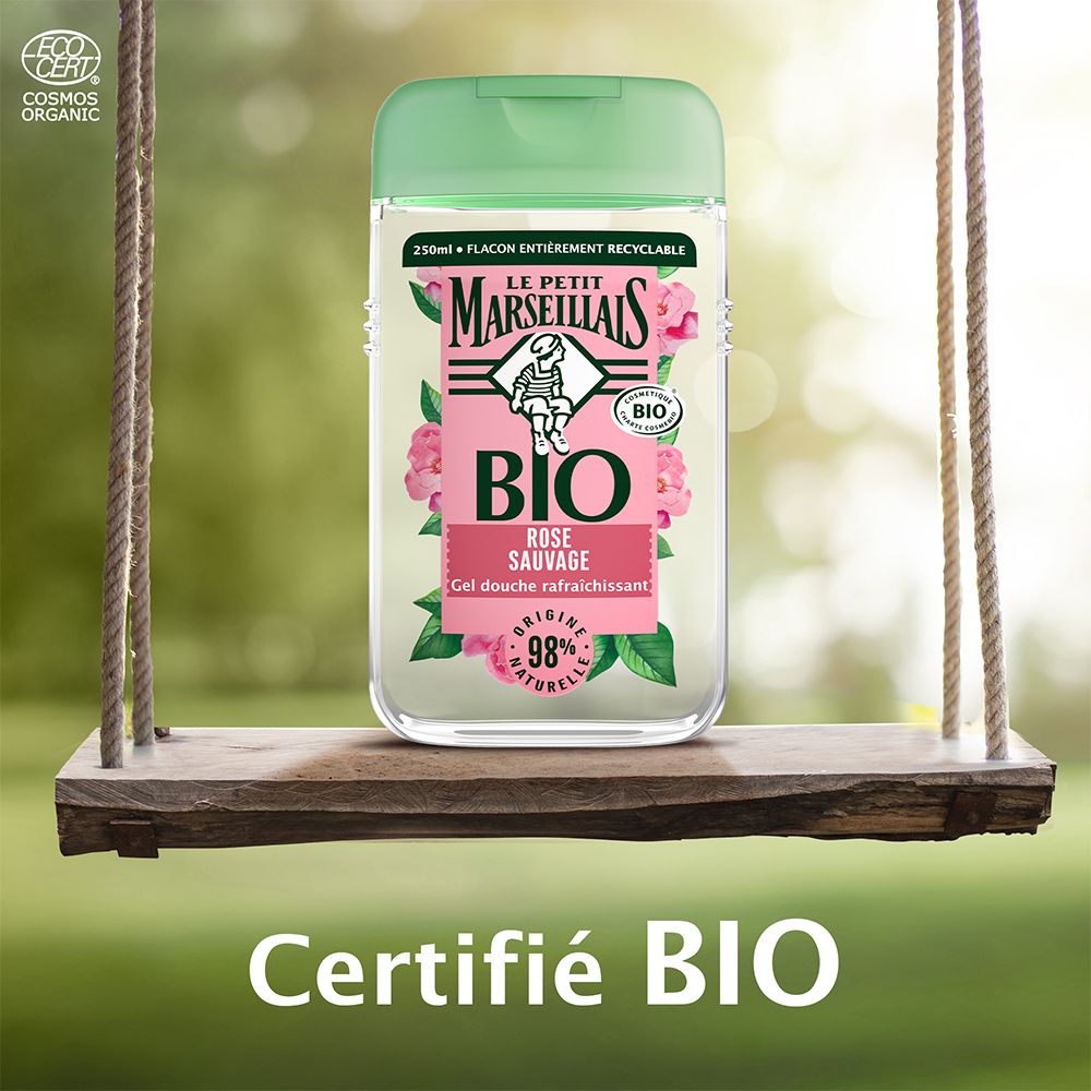 Flacon de gel douche sur une balançoire. Inscription : BIO, Rose sauvage, 98% naturel. Avec certification bio.