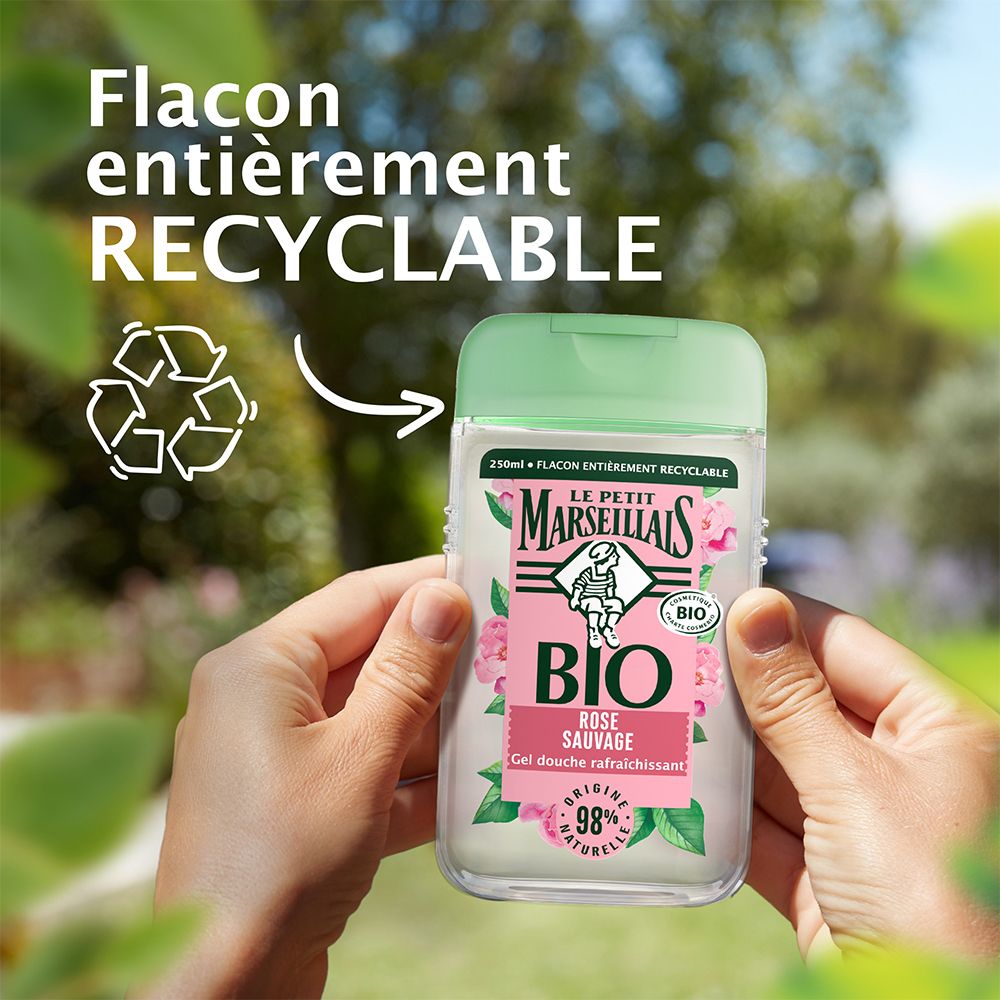 Mains tenant un flacon de gel douche. Inscription : BIO, Rose sauvage, 98% naturel. Flacon recyclable.