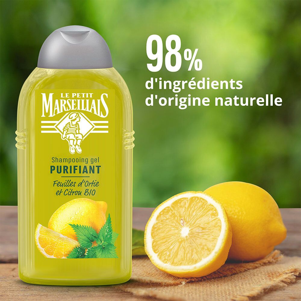 Flacon de shampoing avec étiquette jaune, citron et menthe. Texte : 98% d'ingrédients d'origine naturelle. Sur fond bois.