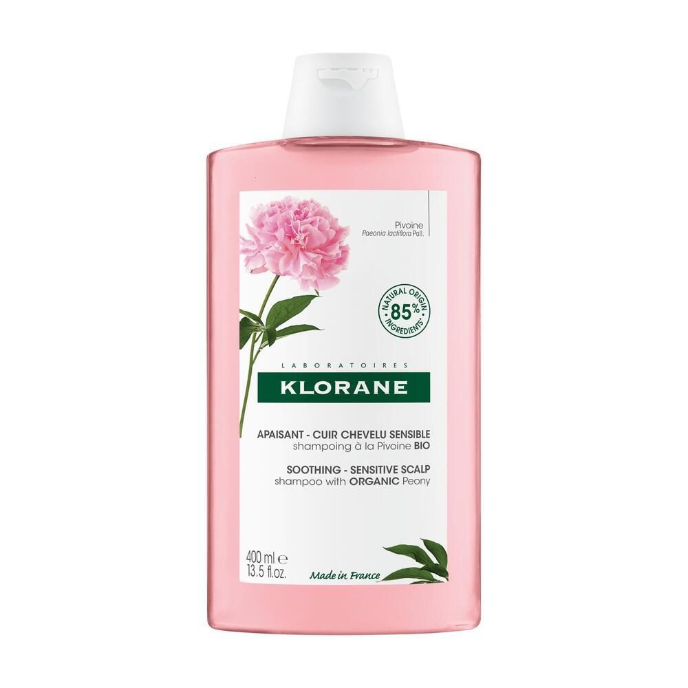 Flacon rose avec bouchon blanc. Étiquette avec pivoine, texte: KLORANE, shampooing apaisant. 400ml.
