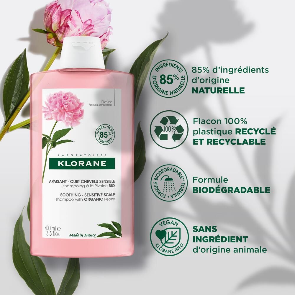 Flacon rose avec bouchon blanc. Texte: KLORANE, shampooing apaisant. Symboles: 85%, recyclable, biodégradable, vegan.