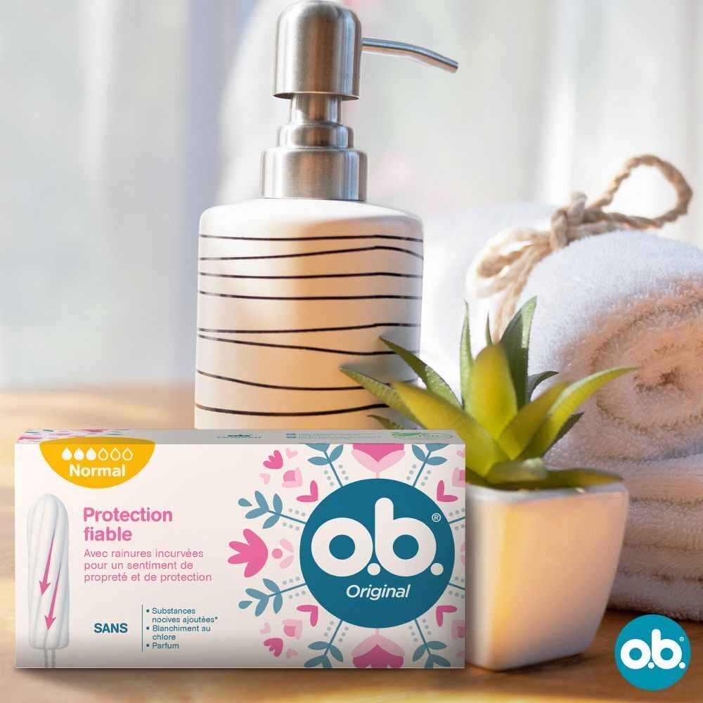 Boîte de tampons o.b.® Original, à côté de serviettes, distributeur de savon et plante. Texte : Normal, Protection, sans substances ajoutées.