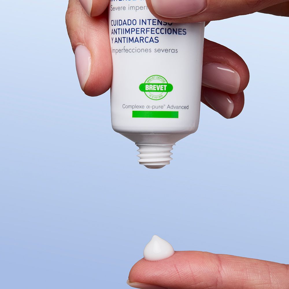 Hand hält Tube. Creme wird auf Finger gedrückt. Produktname nicht sichtbar.