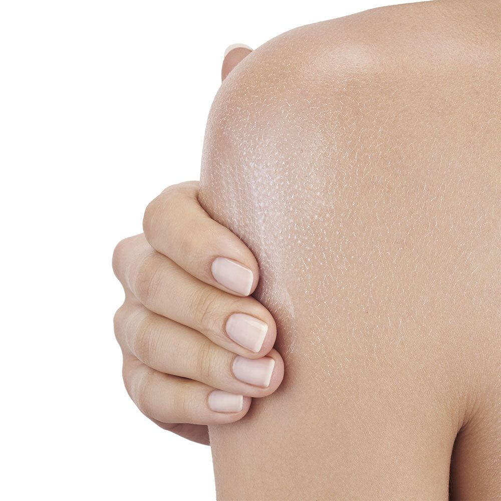 Gros plan sur une épaule avec peau hydratée. Aucune indication de produit visible.