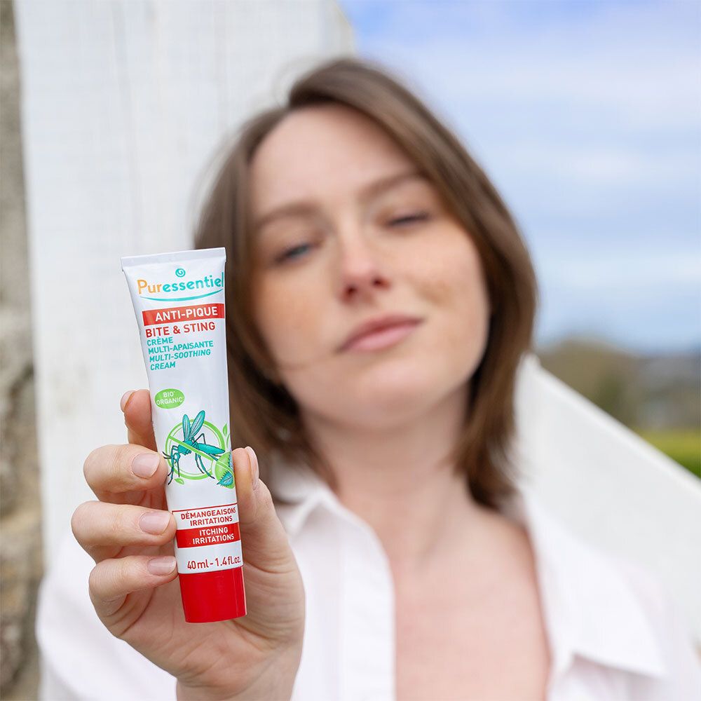 Frau hält Creme-Tube. Aufschrift: Anti-Pique, Multi-Aspirierende Creme gegen Zecken. Bio-Zertifizierung.
