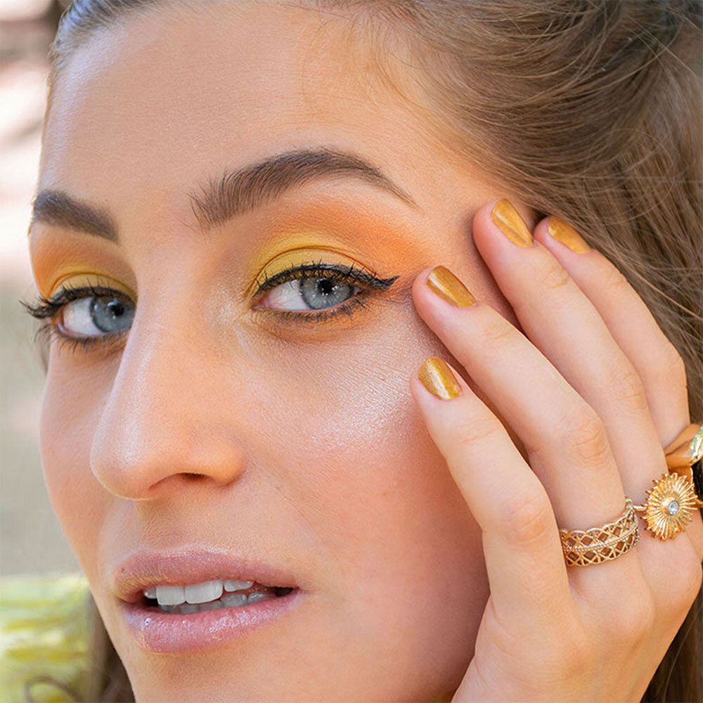 Frau mit Make-up. Gelber Lidschatten, schwarzer Eyeliner, goldene Ringe.