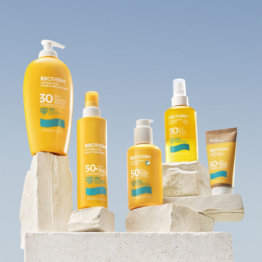 Mehrere Sonnencreme-Produkte auf Felsen. Gelbe Flaschen und Tuben. Aufschrift: BIOTHERM WATERLOVER SPF30/50.