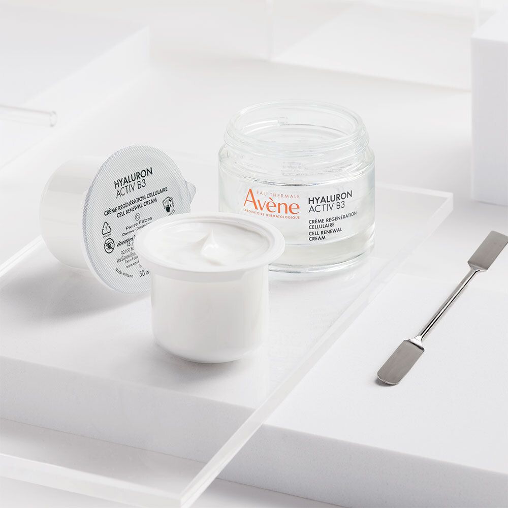 Deux pots de crème et une spatule. Inscription : Avene Hyaluron Activ B3. Un pot ouvert avec de la crème.