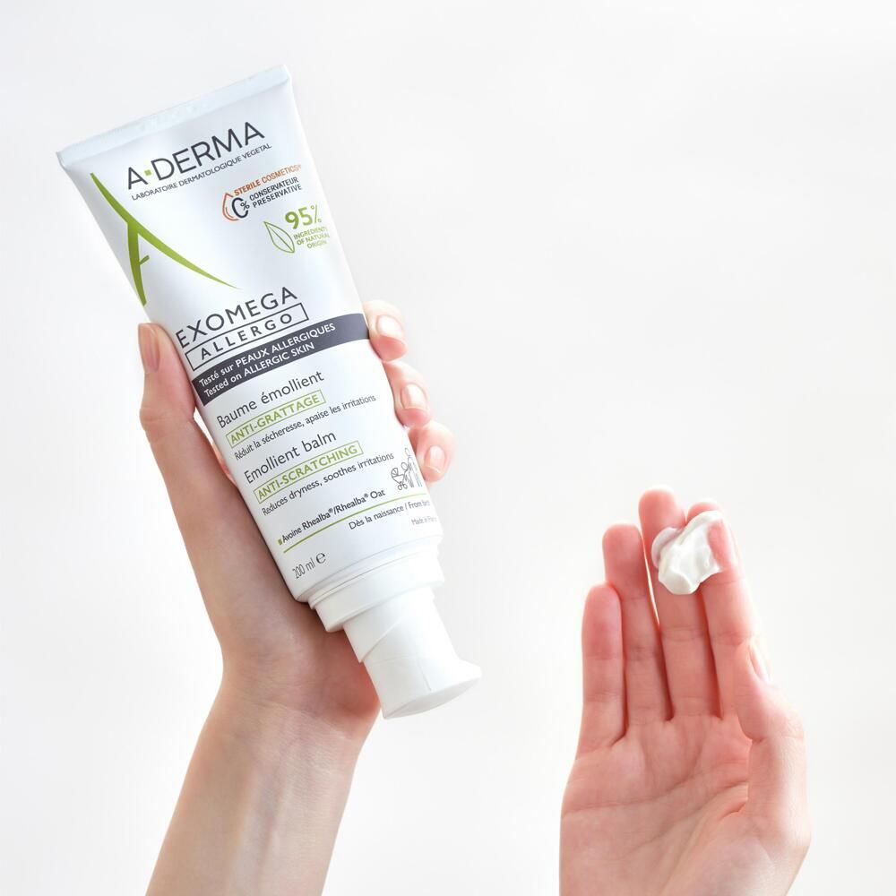 Mains tenant un tube A-DERMA EXOMEGA Allergo. Crème blanche sur la main. Baume anti-grattage.