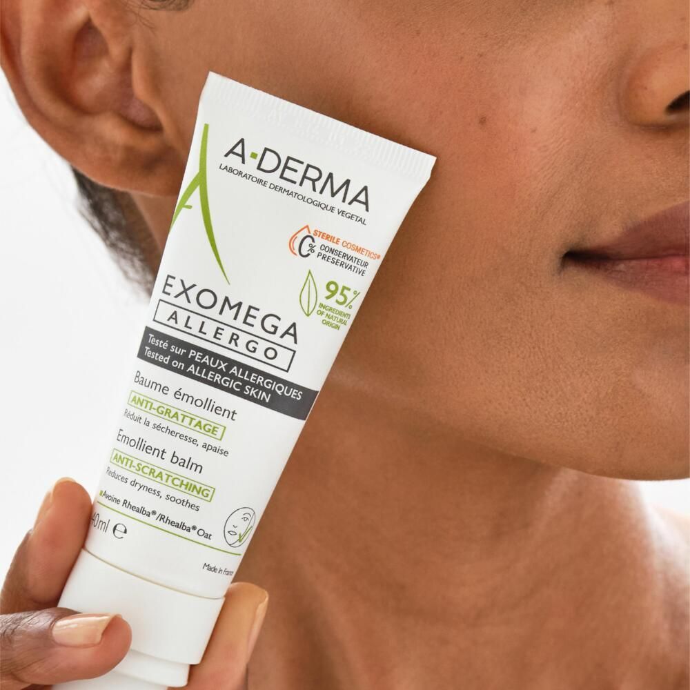 Tube A-DERMA EXOMEGA ALLERGO. Appliqué sur la peau. Visage d'une personne en arrière-plan.