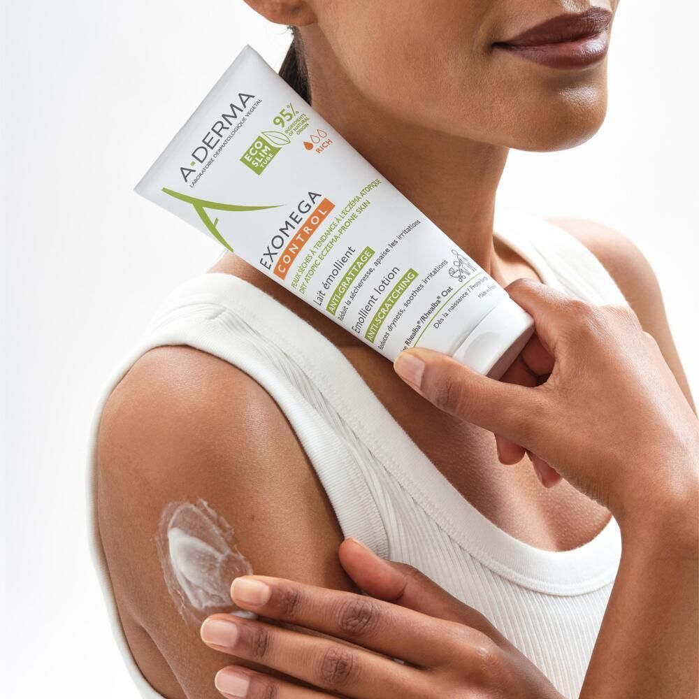 Personne tenant un tube. Elle applique le produit sur son bras. Produit: A-DERMA EXOMEGA CONTROL.