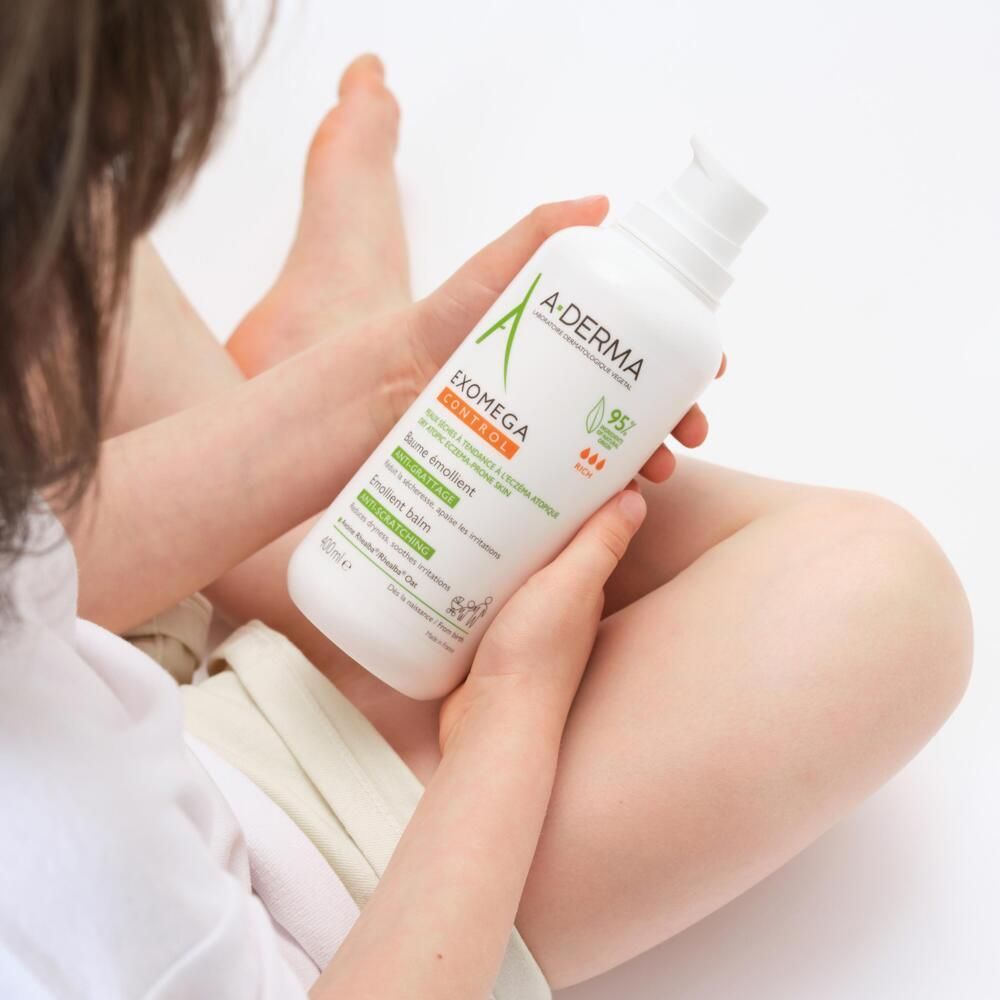 Enfant tenant un flacon A-DERMA EXOMEGA CONTROL. Emballage blanc avec pompe. Étiquettes vertes et orange. 400ml.
