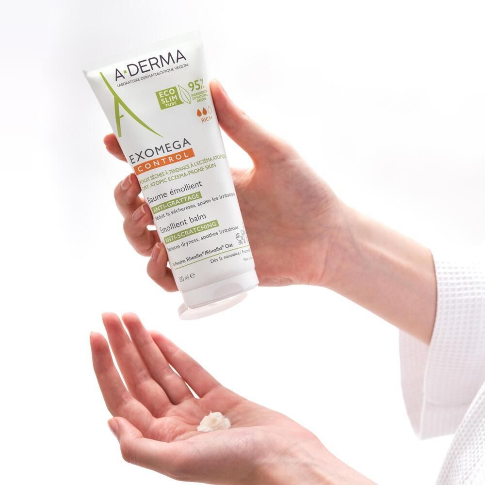 Mains tenant un tube A-DERMA EXOMEGA CONTROL. Une petite quantité de baume est déposée sur la paume.