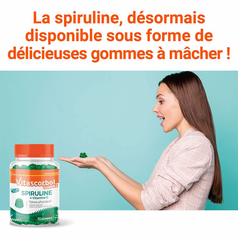 Femme tenant des gommes vertes. Flacon Vitascorbol Spiruline + Vitamine C en arrière-plan.