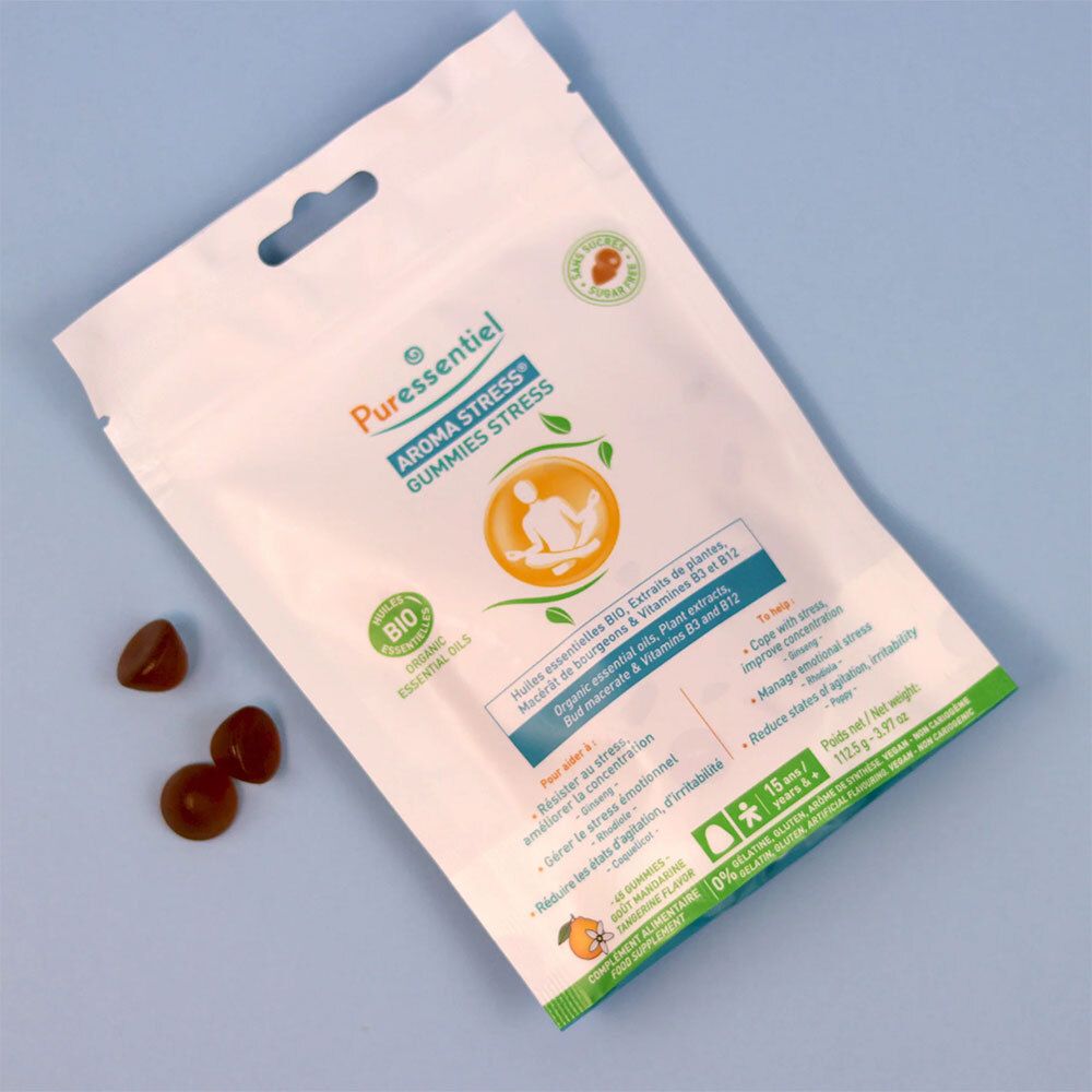 Emballage du produit avec des gummies. Sachet blanc avec des accents verts et oranges. Quelques gummies à côté. Sur fond bleu.