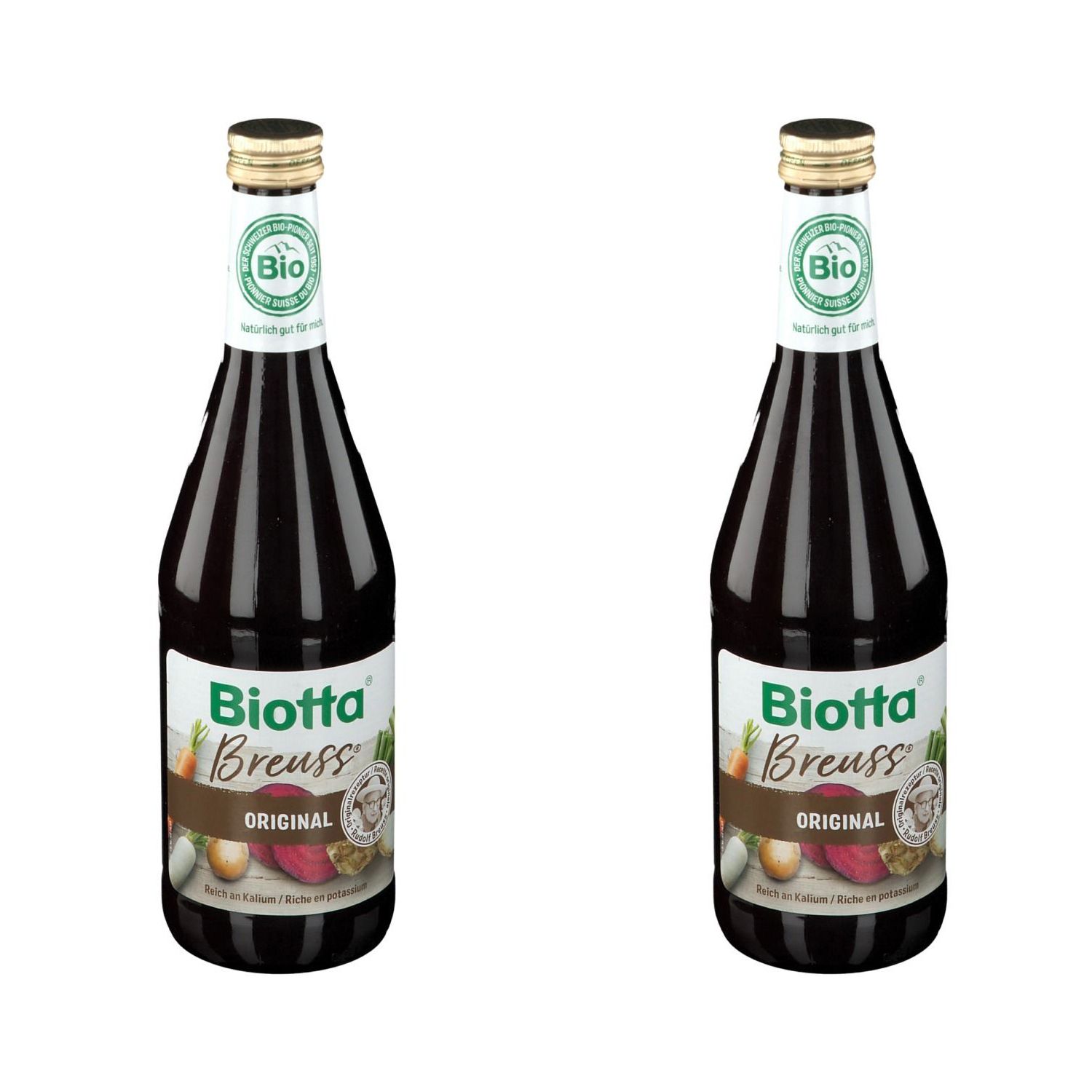 Deux bouteilles de Biotta Breuss Original. Liquide brun dans des bouteilles en verre avec des bouchons dorés. Label bio en haut.