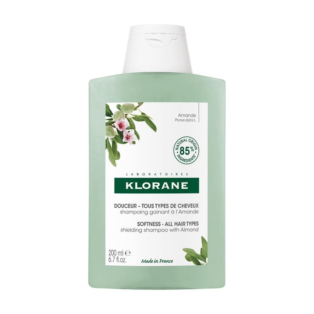 Flacon de shampooing vert clair avec bouchon blanc. Inscription KLORANE, illustration d'amande, 85% ingrédients naturels. Texte: Tous types de cheveux.