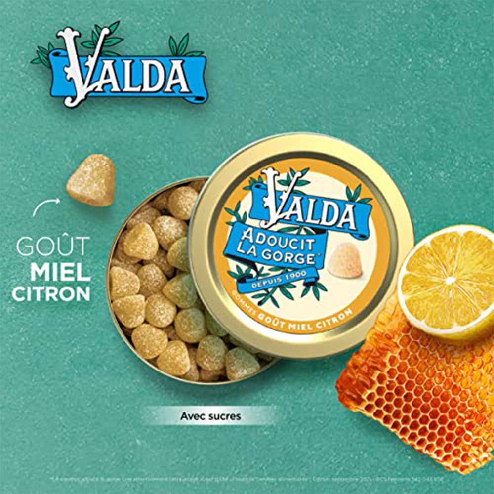 Geöffnete Dose mit Gummibärchen, Zitrone und Honigwabe. Aufschrift: VALDA, Adoucit la Gorge. Gout Miel Citron. Mit Zuckern.